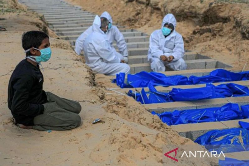 Seorang anak laki-laki berlutut di dekat kuburan para korban tewas dalam konflik Hamas-Israel di kota Rafah di Jalur Gaza selatan, pada Selasa (30/1/2024). - Image