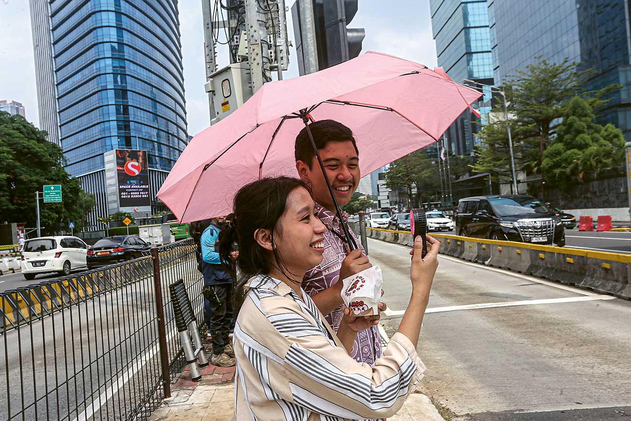 HINDARI TERIK: Pejalan kaki menggunakan payung untuk menghindari terik matahari di Jakarta, Kamis (2/5). - Image