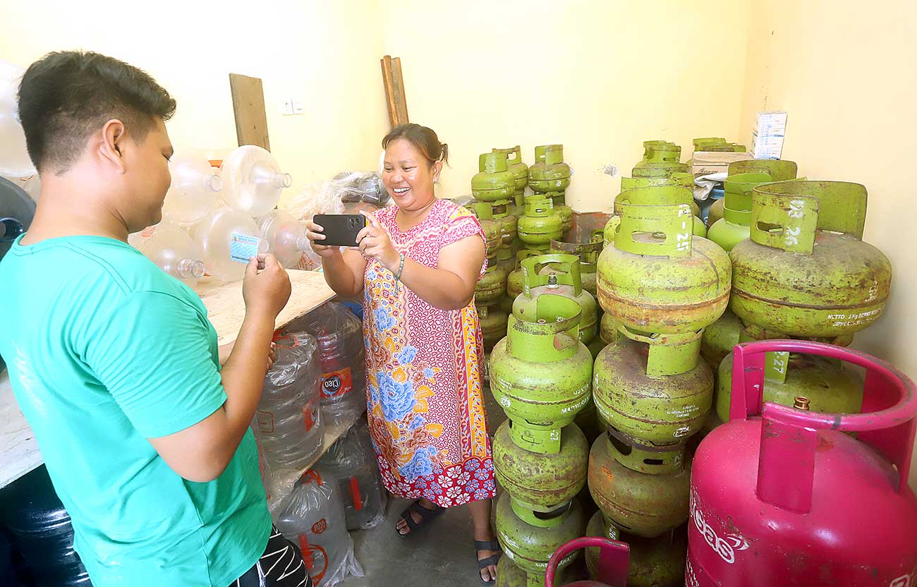 ATURAN BARU: Rusnawati memotret KTP warga yang membeli gas elpiji 3 kg di kawasan Krembangan, Surabaya (2/6). - Image