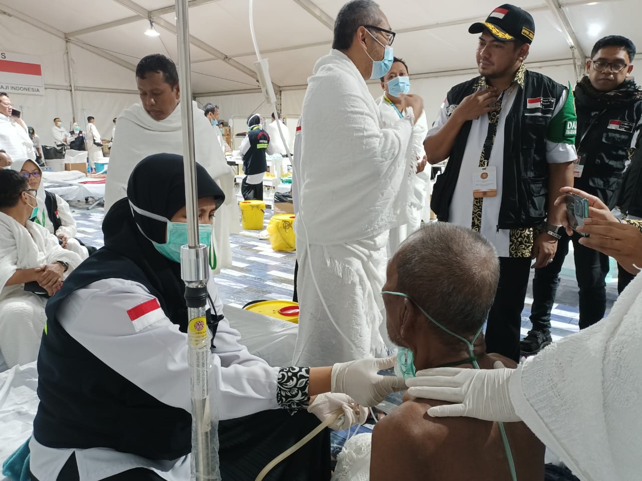 Ditangani: Hasan Basri (duduk membelakangi kamera) ditangani perawat akibat tenggorokannya tersedak bolu di KKHI tenda misi haji Arafah. - Image