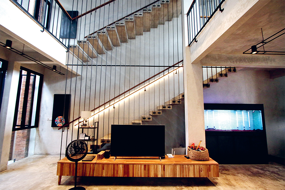 STAIR LIGHTING: Permainan pencahayaan pada sisi tangga kian menonjolkan desain industrial yang berkesan hangat.