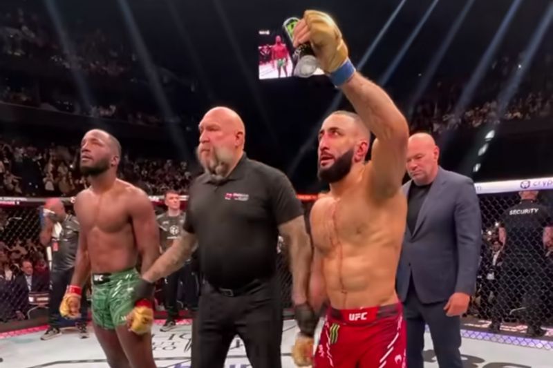 Belal Muhammad (kanan) mengangakat tangan pada saat dirinya jadi pemenang dalam pertarungan lawan Leon Edward untuk perebutan gelar juara kelas welter UFC 305 - Image