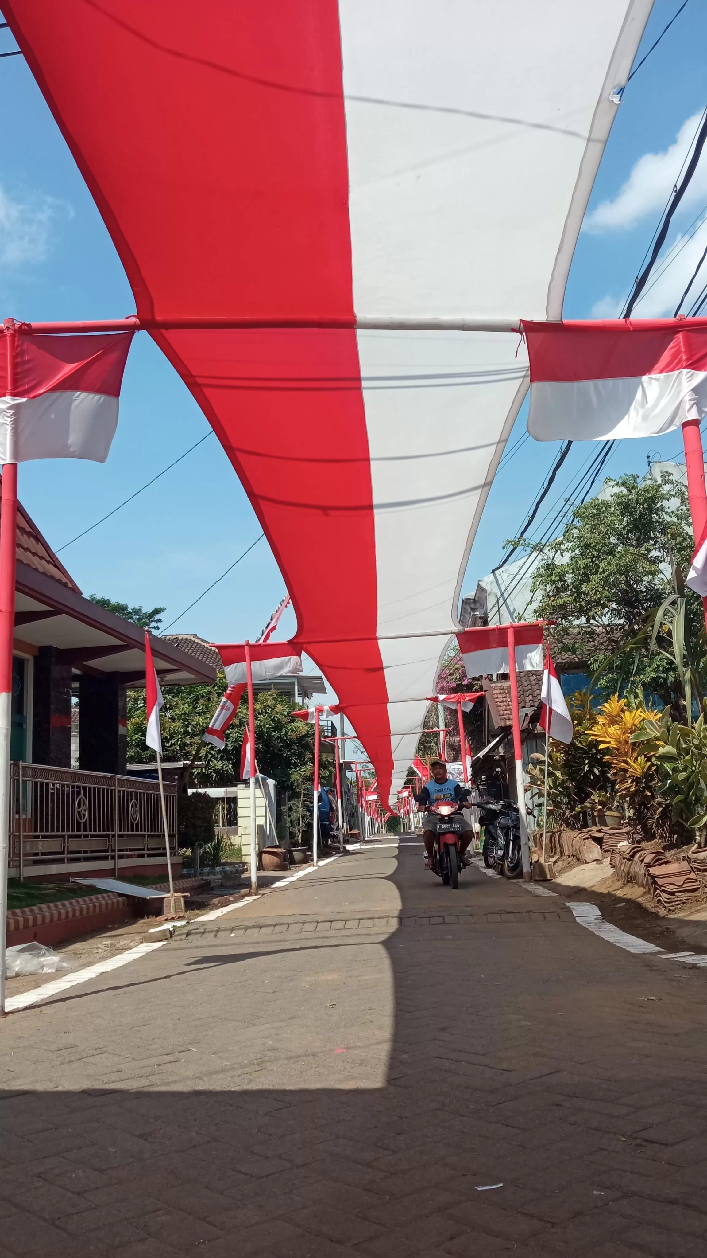 ANTUSIASME: Warga RT 37 RW 06 Dusun Sememek, Desa Kebonagung, Kecamatan Pakisaji membentangkan merah putih di jalan kampung kemarin. (RadarMalang) - Image