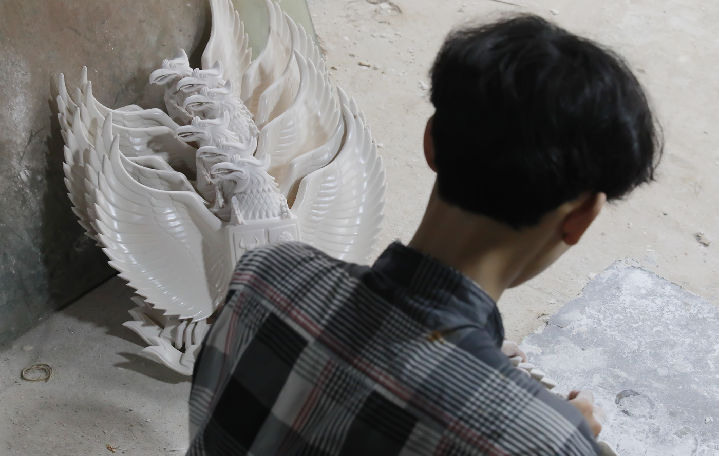 Pengrajin melakukan pengecatan patung lambang negara Garuda Pancasila berbahan serat kaca (fiberglas