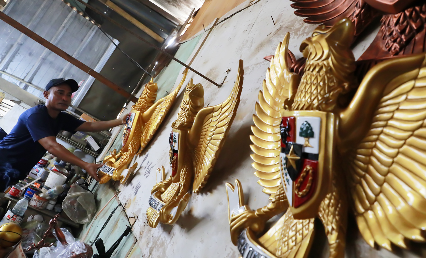 Pengrajin melakukan pengecatan patung lambang negara Garuda Pancasila berbahan serat kaca (fiberglas