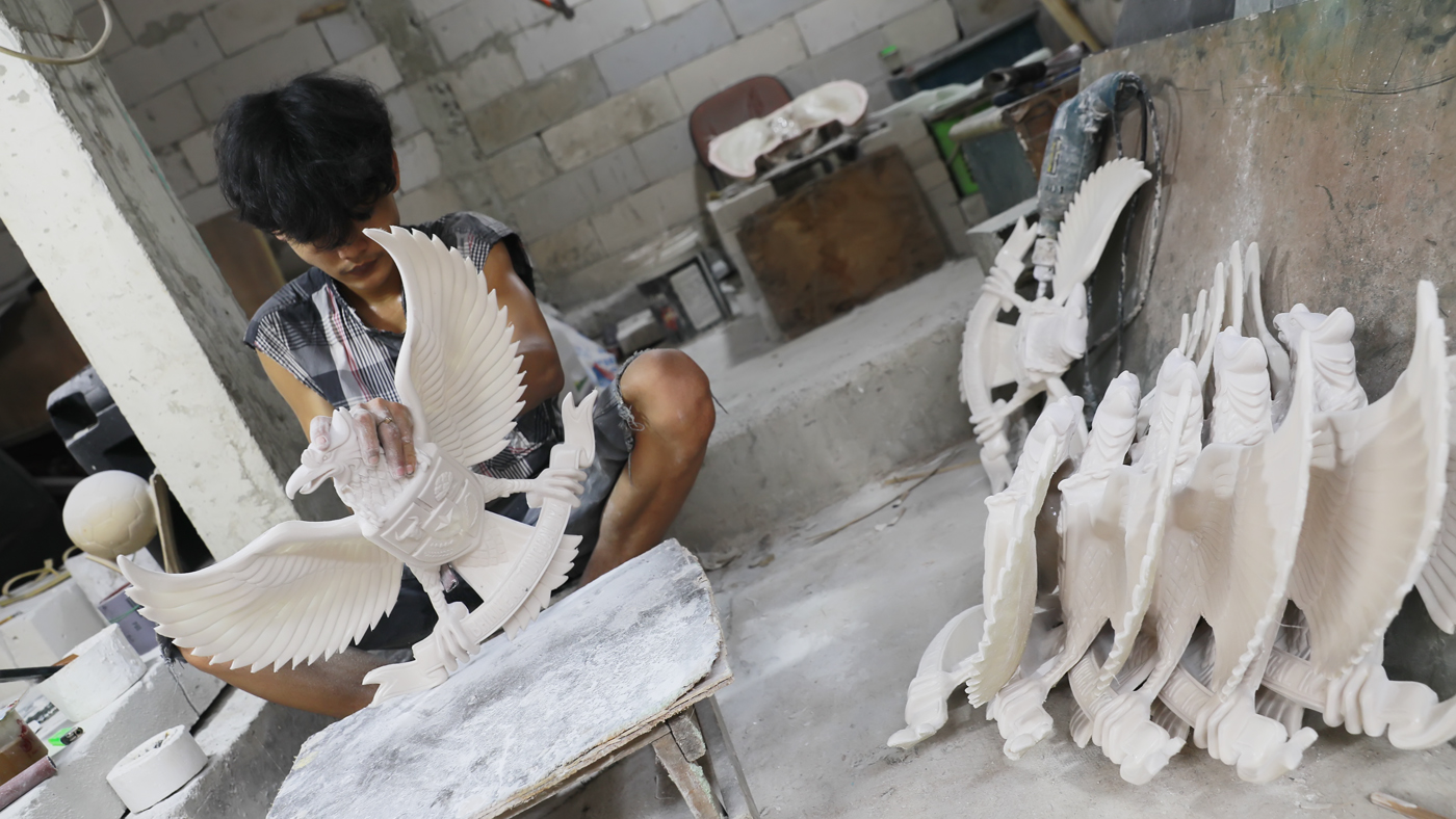 Pengrajin melakukan pengecatan patung lambang negara Garuda Pancasila berbahan serat kaca (fiberglas