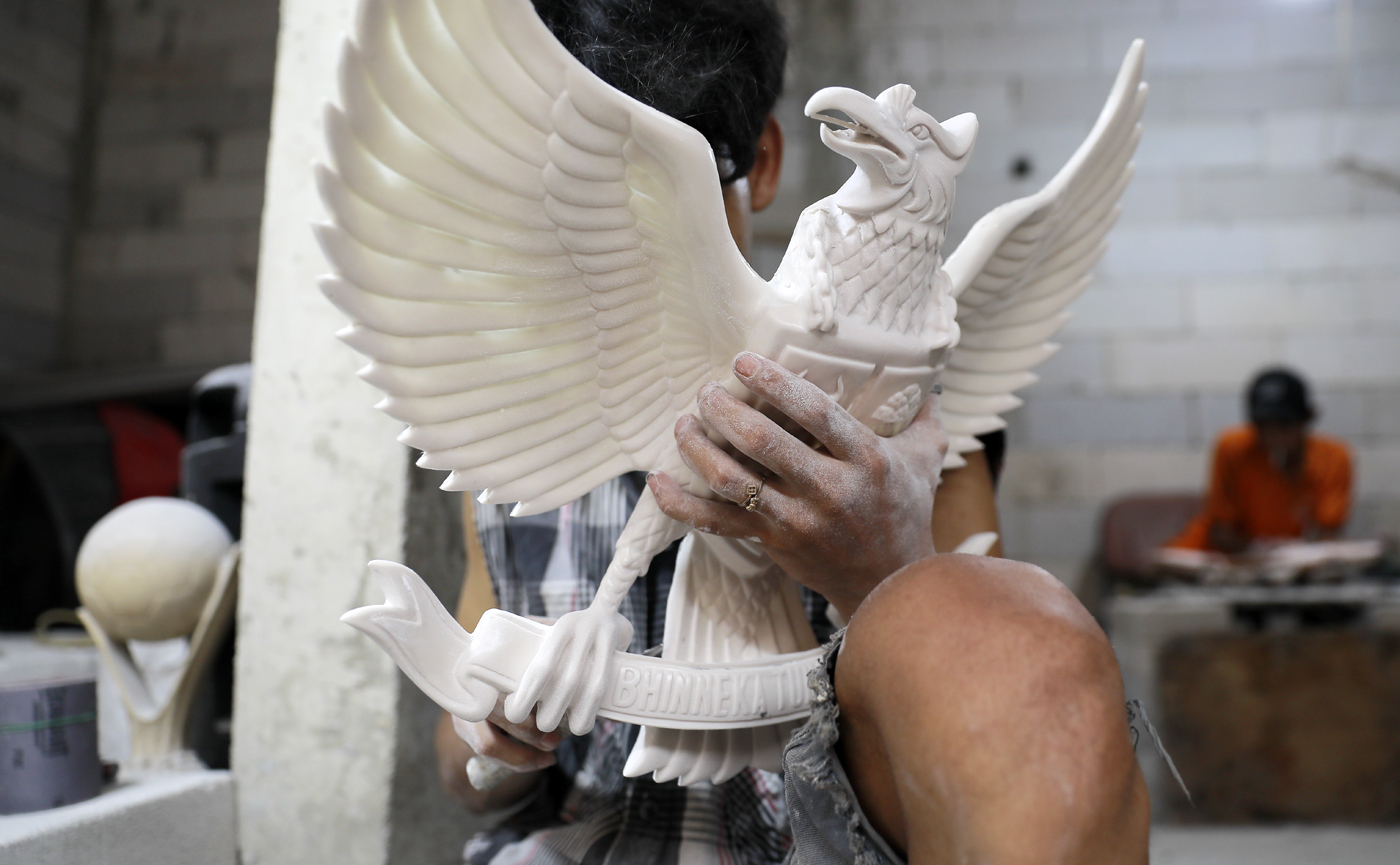 Pengrajin melakukan pengecatan patung lambang negara Garuda Pancasila berbahan serat kaca (fiberglas