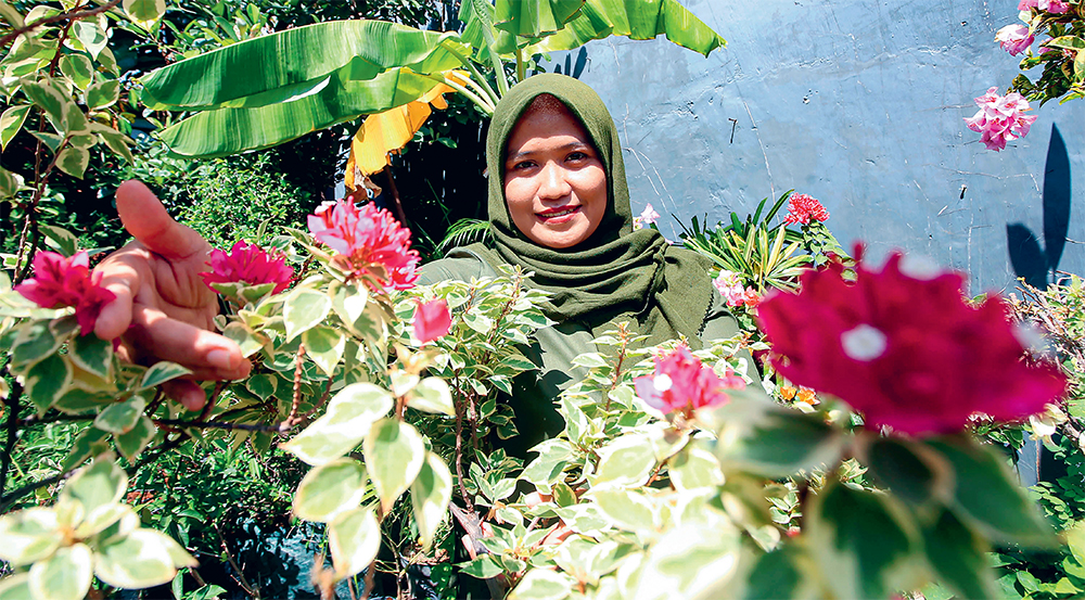 RAJIN PRUNING: Nofitasari bersama sebagian koleksi bugenvil saat dijumpai di Omah Kembang, kawasan Sidosermo, Surabaya, pada Jumat (23/8). (DIMAS MAULANA/JAWA POS) - Image
