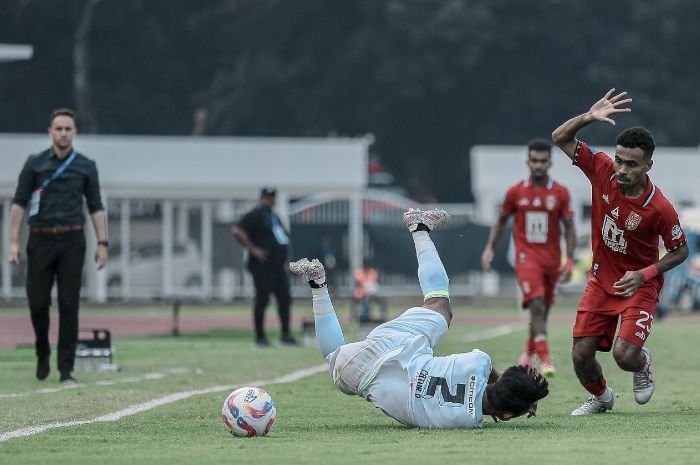 Momen Arief Catur Pamungkas jatuh usai berduel dengan pemain Malut United, Yakob Sayuri, dalam pertandingan melawan Malut United pada 16 Agustus lalu di Stadion Madya. (persebaya.id) - Image