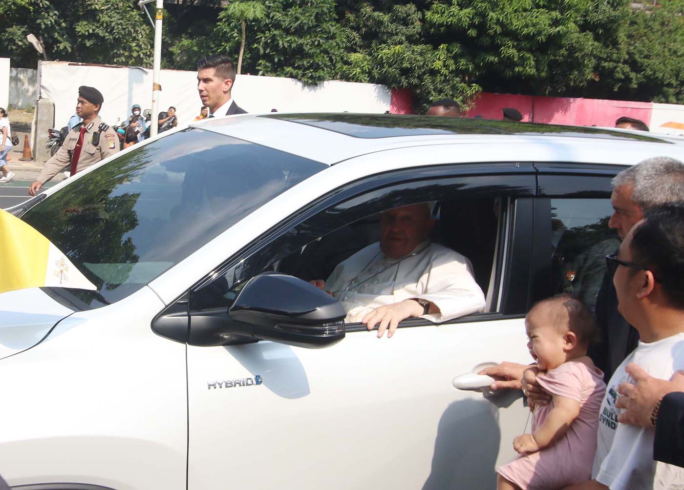 Paus Fransiskus menyapa masyarakat yang menunggu di Jalan Gambir Jakarta sebelum meninggalkan Indonesia menuju Bandara Internasional Soekarno Hatta, Tangerang, Banten, Jumat (6/9/2024). (Fedrik Tarigan/ Jawa Pos) - Image