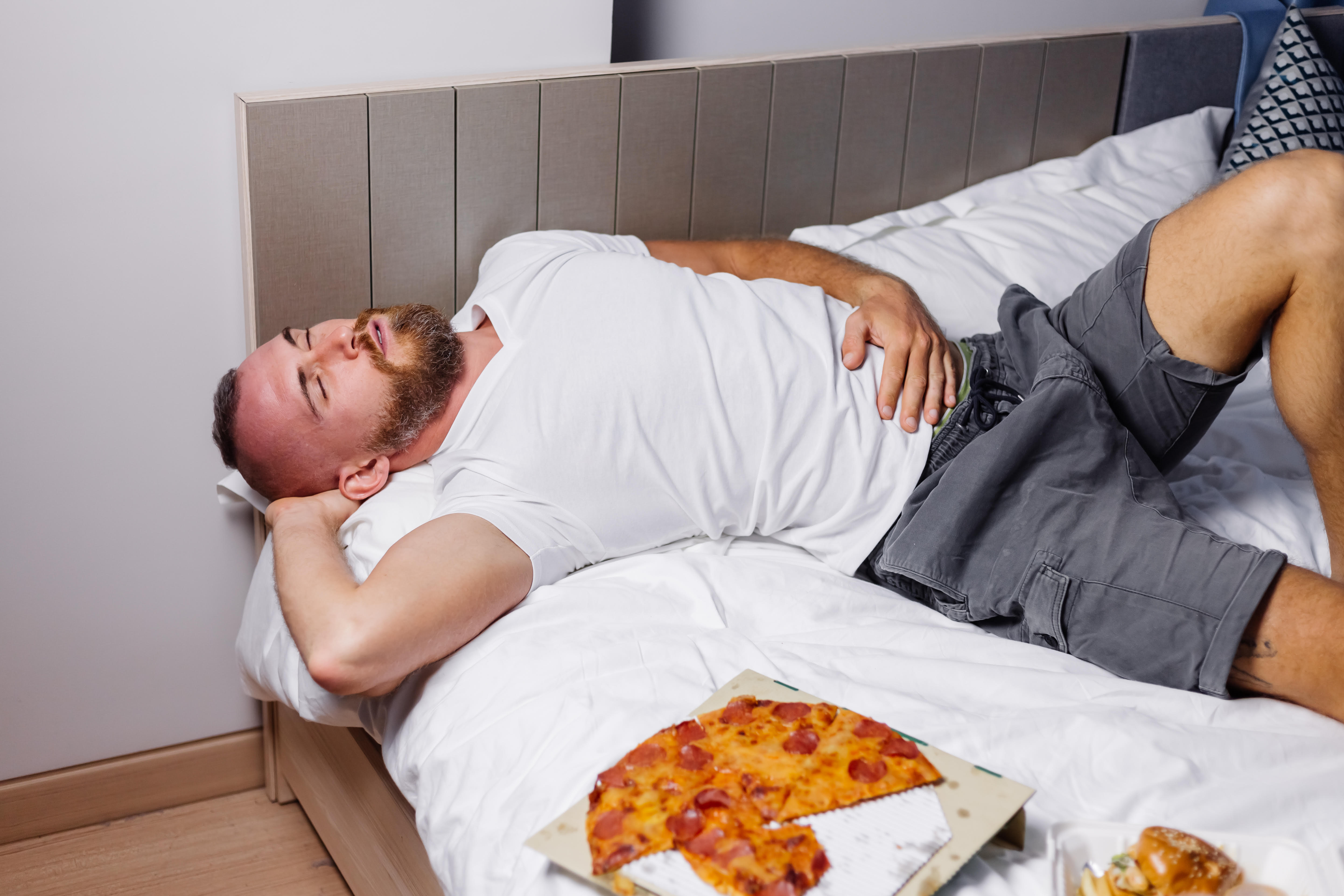 Ilustrasi seorang pria yang tidur setelah makan pizza. (Freepik/kroshka_nastya) - Image