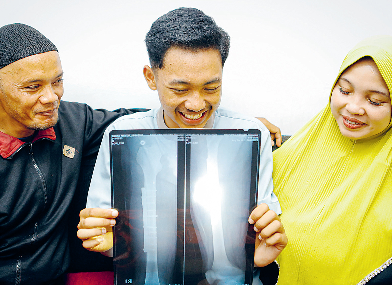 Achmad Hadi Mulyo, korban patah kaki dalam Tragedi Kanjuruhan diapit kedua orang tua kemarin. (DIPTA WAHYU/JAWA POS) - Image