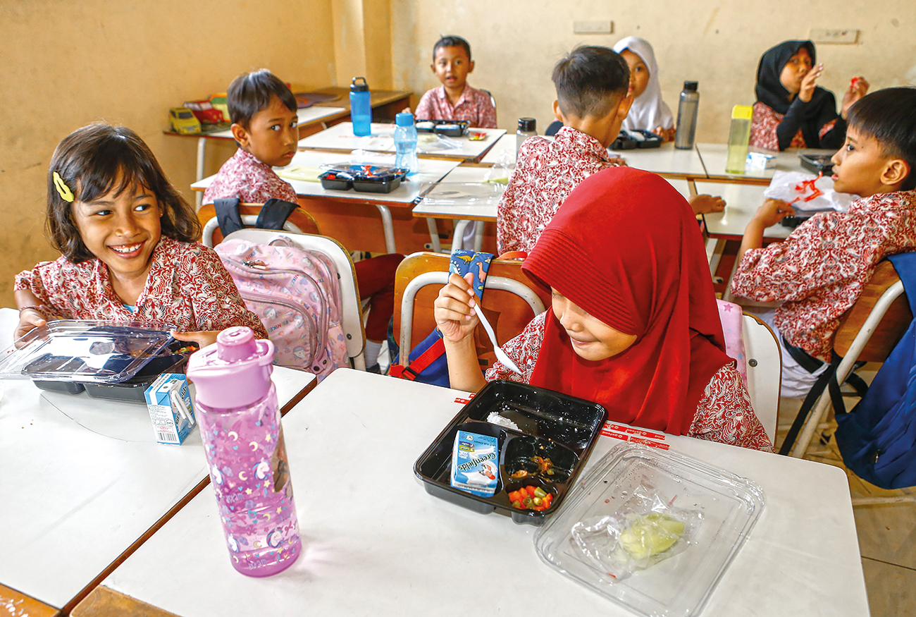 Murid SDN Wonorejo V Surabaya menyantap makanan bergizi gratis pada uji coba Oktober lalu. Dewan dan pemkot menghitung kebutuhan makan bergizi gratis tembus Rp 1 triliun. (Dipta Wahyu/Jawa Pos) - Image