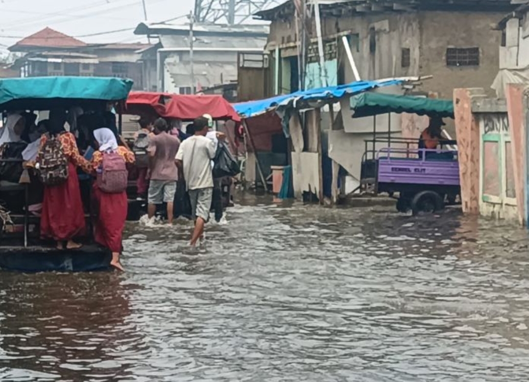 Sejumlah pelajar menaiki kendaraan yang melaju di atas genangan air di kawasan Muara Baru Penjaringan Jakarta Utara pada Jumat (15/11/2024 pagi. (ANTARA/Dokumentasi Pribadi) - Image