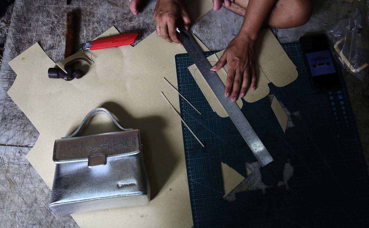 Perajin menyelesaikan pembuatan tas di ruang kerja usaha mikro, kecil, dan menengah (UMKM) pembuatan tas kulit Biyantie di kawasan Kalibata, Jakarta Selatan, Jumat (15/11/2024). (Fedrik Tarigan/ Jawa Pos) - Image