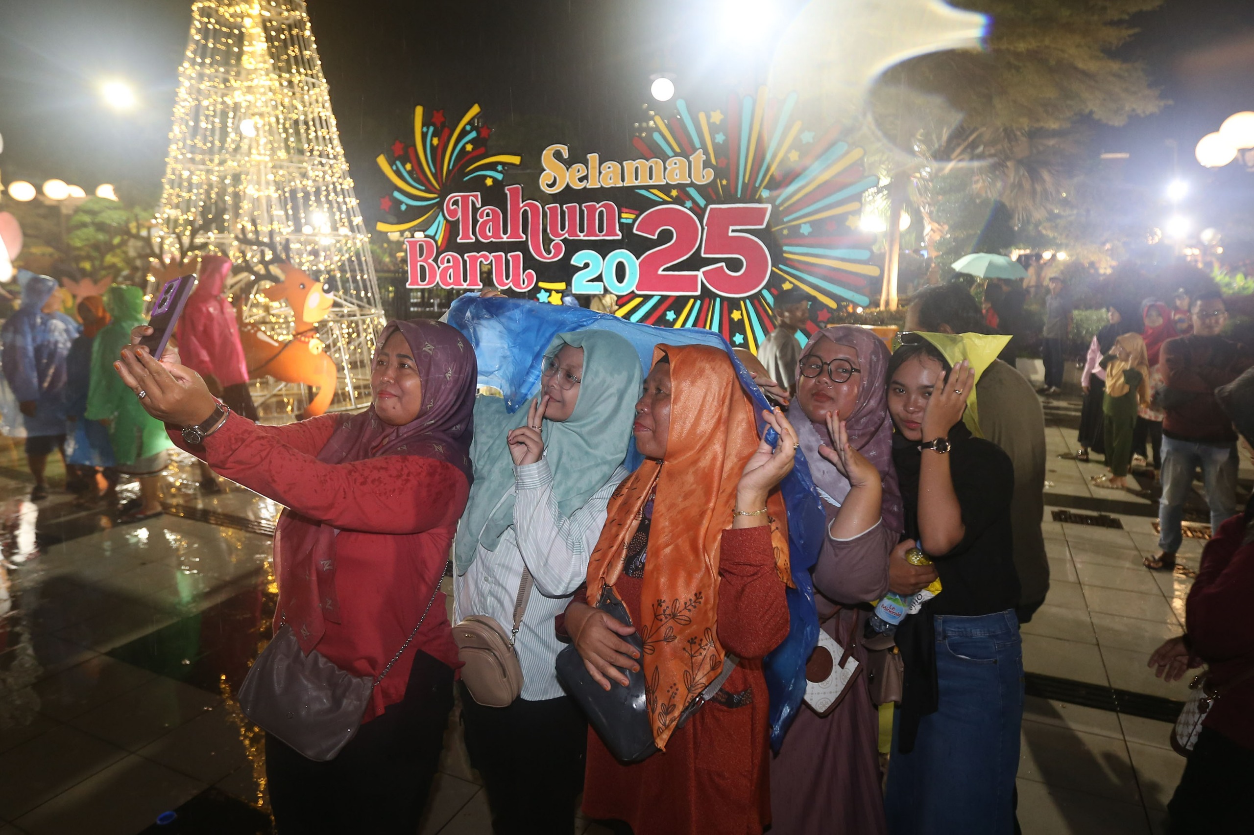 Warga mengabadikan momen pergantian tahun baru dengan semangat meski hujan turun. (Istimewa). - Image