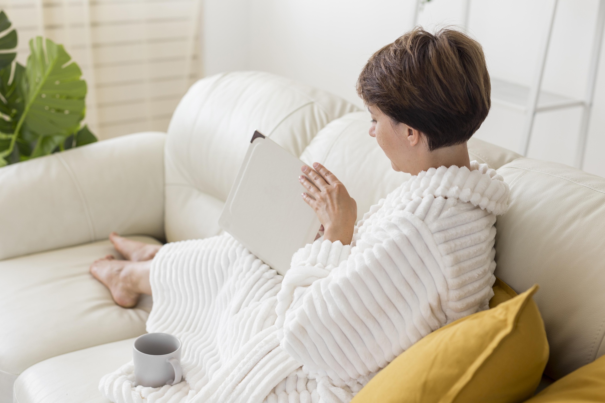 Ilustrasi seorang perempuan yang duduk di sofa sambil membuka album foto. (freepik) - Image