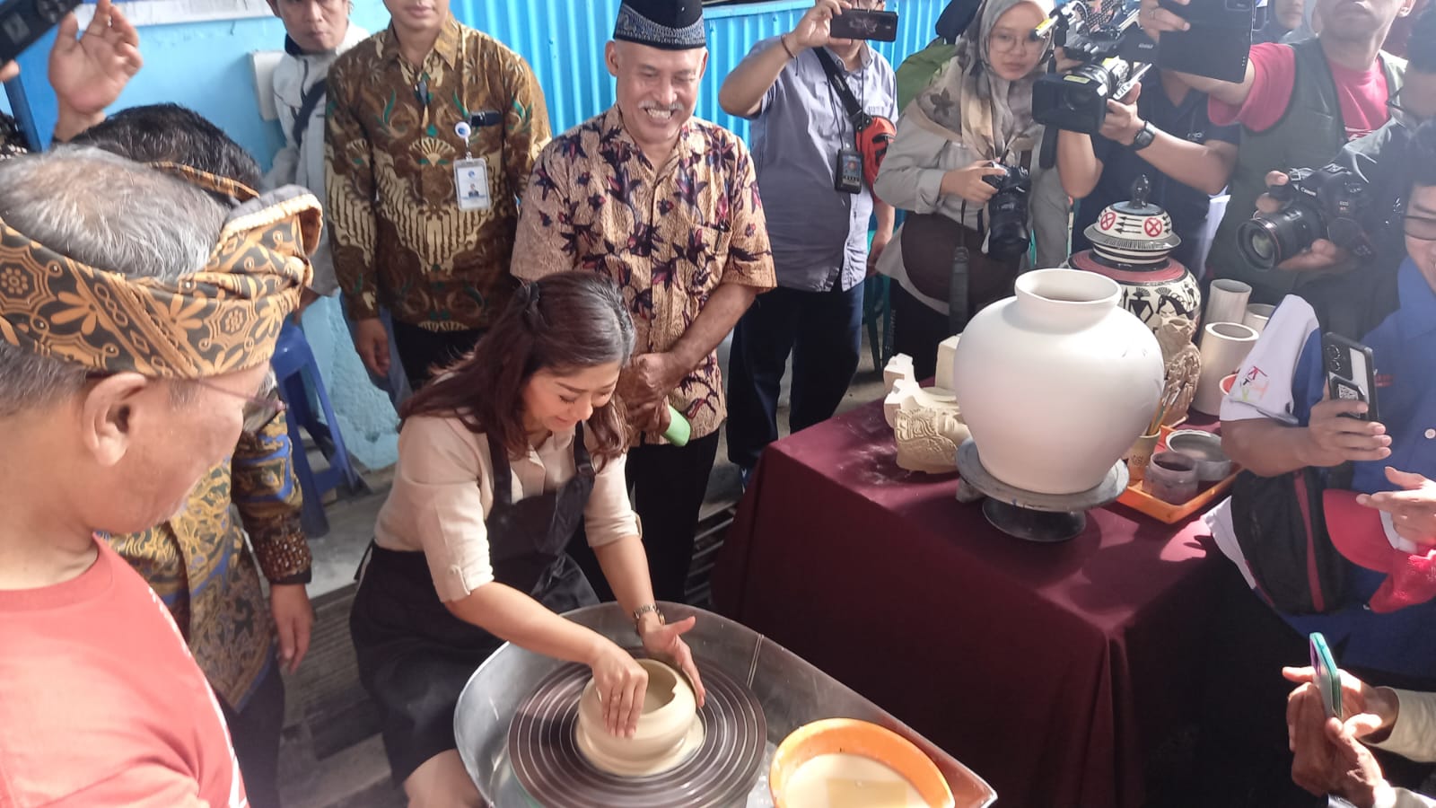 Menteri Komunikasi dan Digital Meutya Hafid mencoba membentuk keramik dari tanah liat di Kampung Wisata Dinoyo, Kecamatan Lowokwaru, Kota Malang, pada Sabtu (4/1). (ILHAM SAFUTRA/JAWAPOS.COM) - Image