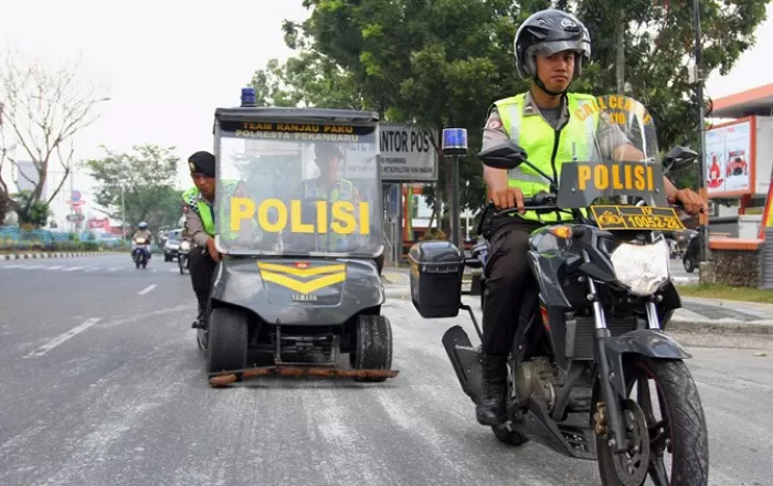 Ilustrasi: Aparat kepolisian membersihkan ranjau paku di jalanan. (Istimewa) - Image