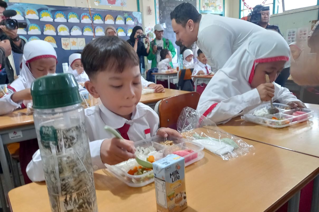 Siswa SD Taquma Surabaya tampak layap menyantap Makan Bergizi Gratis hari pertama. (Novia Herawati/JawaPos.com) - Image