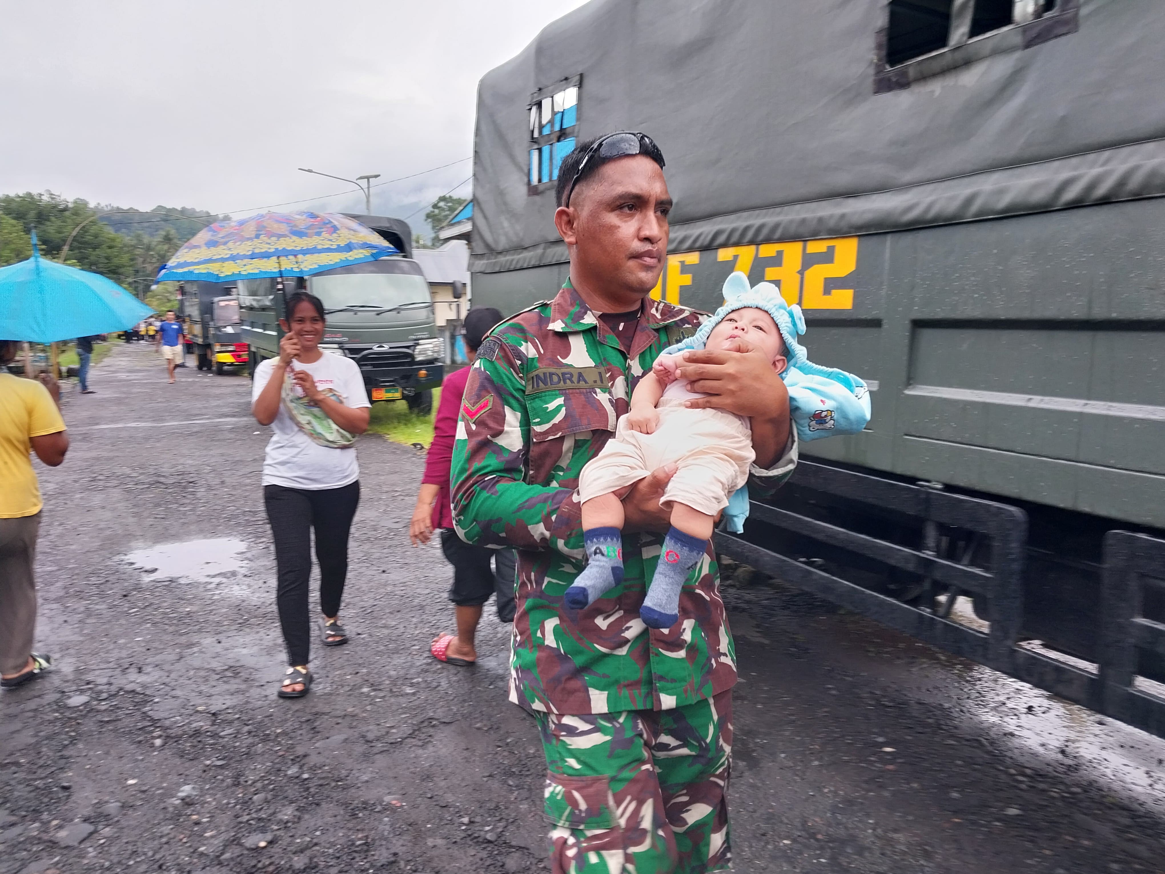 Sejumlah prajurit TNI mengevakuasi warga dari Desa yang berada di radius berbahaya erupsi Gunung Ibu. (BNPB). - Image