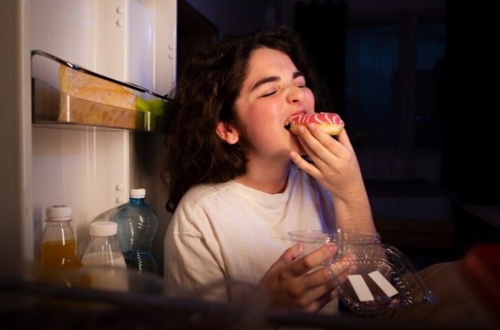 Ilustrasi orang yang mengonsumsi makanan secara berlebihan saat stres. (freepik) - Image