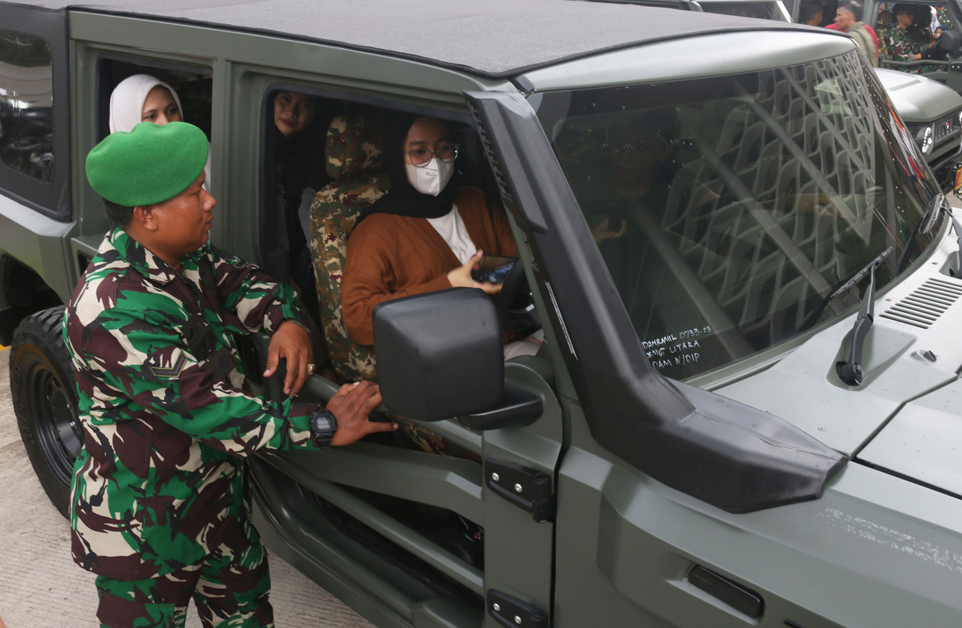 Warga  menaiki kendaraan khusus (Ransus) Jeep Maung MV3 Pindad di sela-sela konvoi dari Makodim 0733