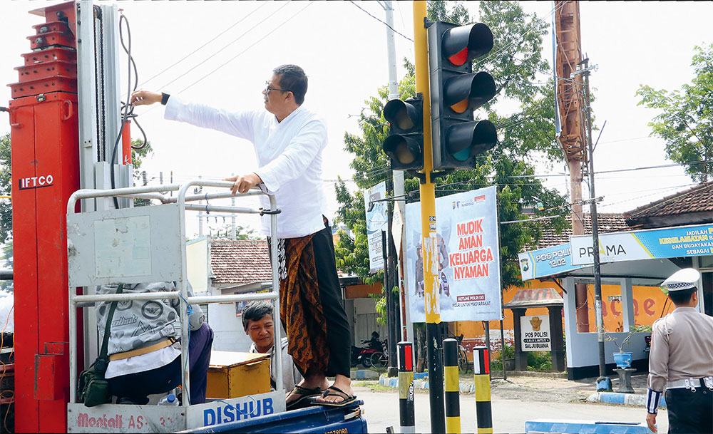MERASA NYAMAN: Kabid Lalu Lintas dan Sapras Dishub Ponorogo Setyo Budiono menaiki crane untuk memantau perbaikan traffic light, Selasa (18/3). (SUGENG DWI N/JAWA POS RADAR PONOROGO) - Image