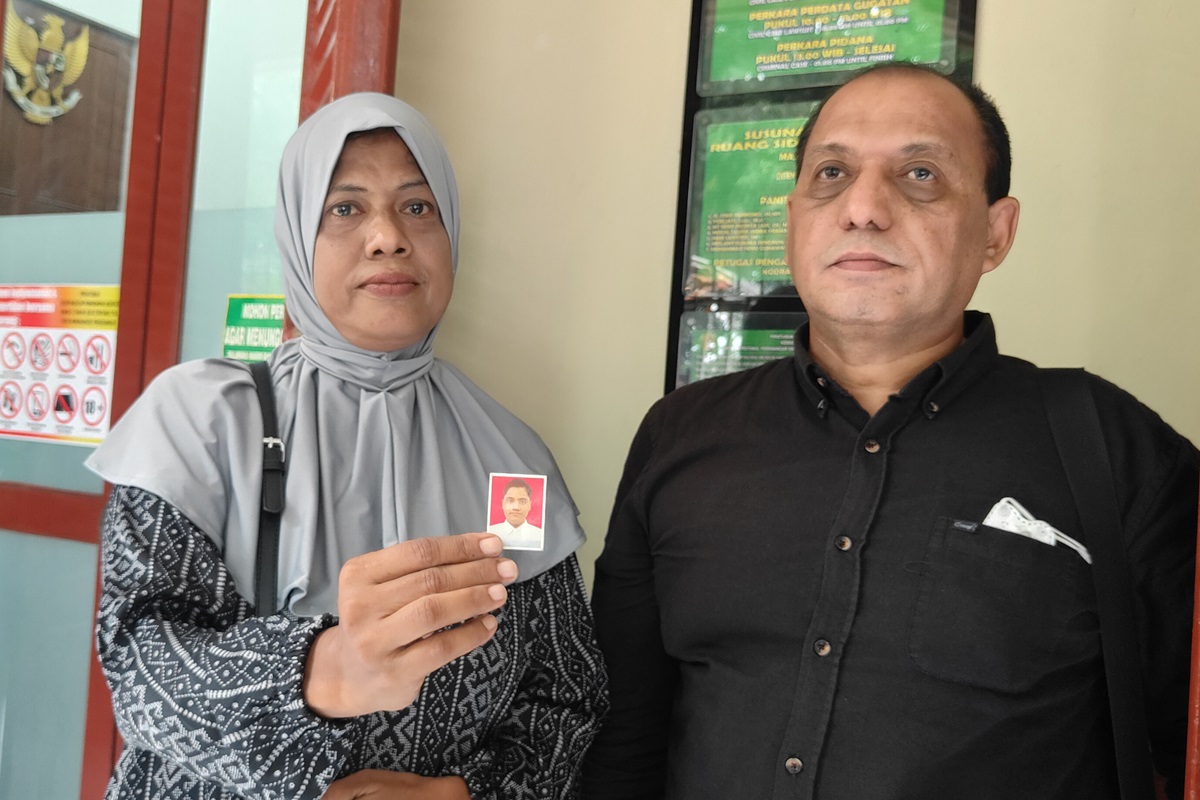 PERJUANGKAN KEADILAN: Hodidjah didampingi kuasa hukum Abdul Kadir menunjukkan foto buah hatinya, M. Zaini Ghonni, yang meninggal akibat pengeroyokan. (Sholeh Hilmi/Jawapos) - Image