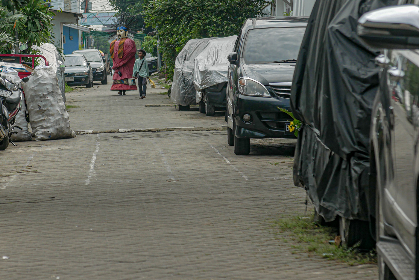 Seorang pengamen Ondel-Ondel melintas di daerah Cibodas, Kota Tangerang, Banten, Senin (19/5/2025).