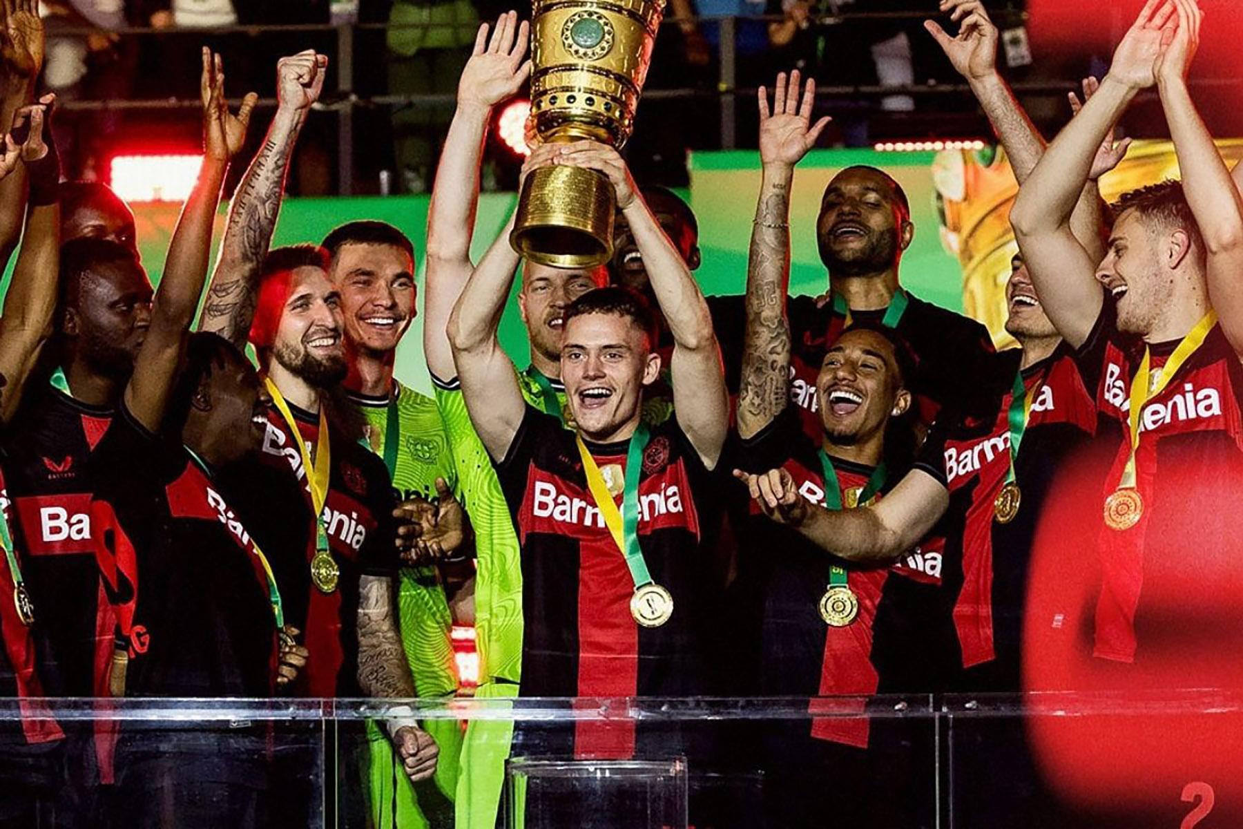 Florian Wirtz mengangkat trofi emas DFB-Pokal dikelilingi rekan-rekan setimnya. (Flowirtz/Instagram) - Image