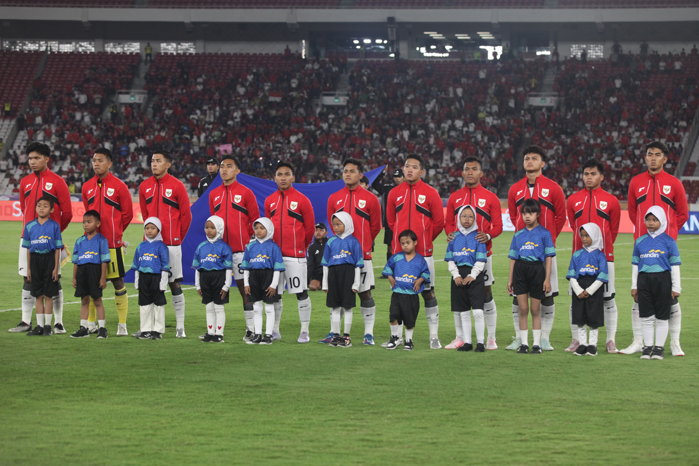 Anak-anak player escort menyanyikan lagu Indonesia Raya bersama para Timnas Indonesia U-23 dalam laga penyisihan Grup A Piala AFF U-23 2025 di Stadion Utama Gelora Bung Karno (SUGBK), Senayan, Jakarta, Jumat (18/7/2025). (Dery Ridwansah/ JawaPos.com) - Image