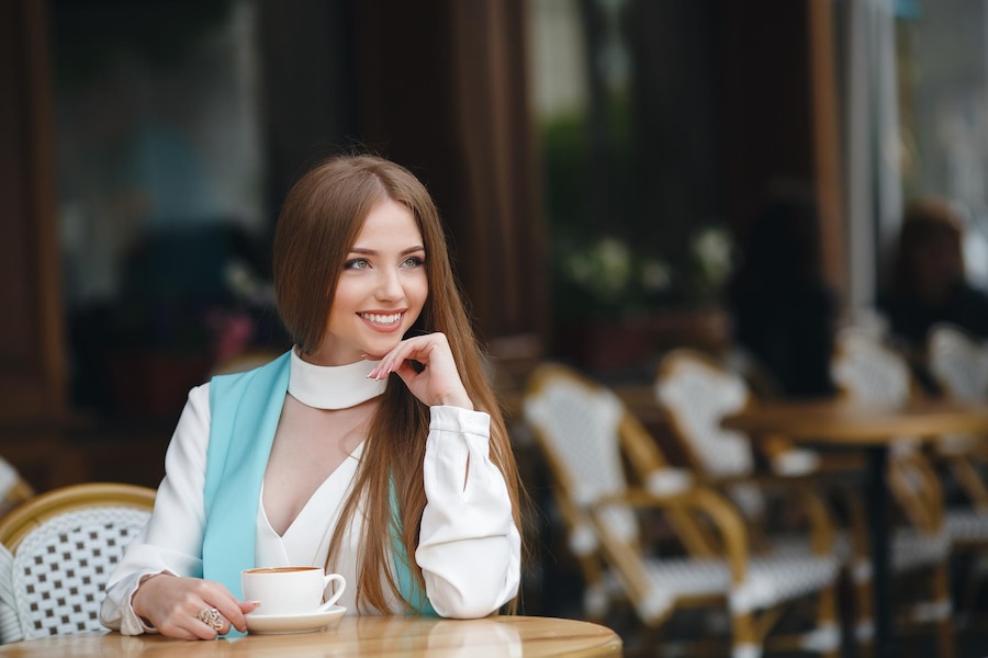 Seorang wanita tersenyum elegan, memancarkan aura kepercayaan diri dan pesona alami. (Freepik) - Image