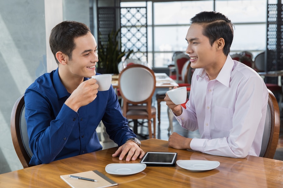 Seorang pria tersenyum sambil berbicara dalam suasana percakapan yang hidup, menunjukkan kecerdasan cepatnya melalui ekspresi wajah dan bahasa tubuh./Freepik - Image