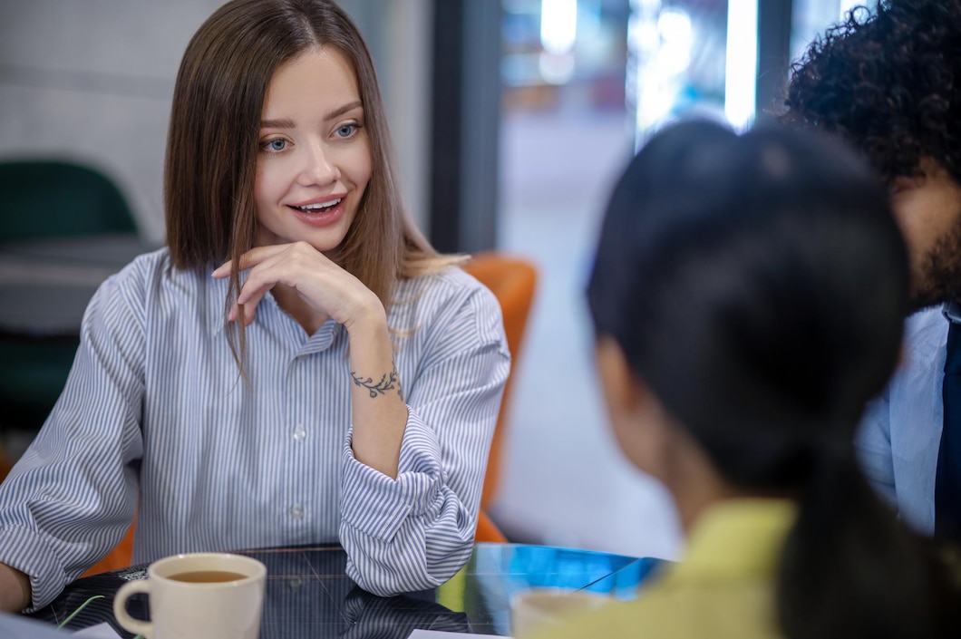 Seorang individu tersenyum saat mendengarkan temannya berbicara, menunjukkan perhatian tulus dan koneksi yang mendalam./Freepik - Image