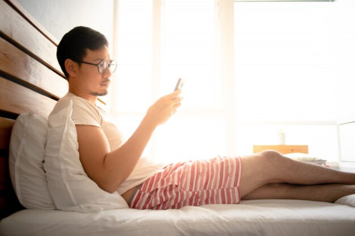 seseorang yang memeriksa ponsel setelah bangun pagi./Freepik. - Image