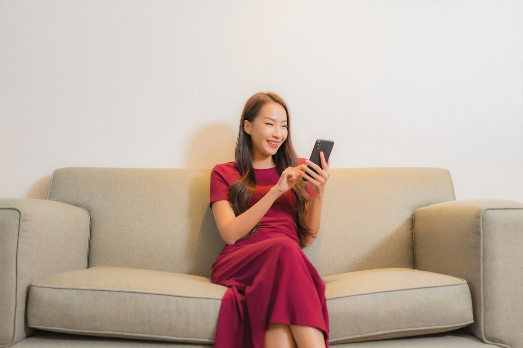 Ilustrasi seseorang yang duduk di sofa sambil melihat ponselnya, dengan cahaya layar memantul di wajahnya, mencerminkan aktivitas mengamati media sosial./Freepik - Image