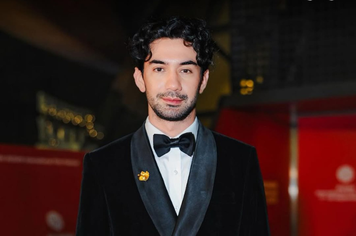 Reza Rahadian memakai tuxedo klasik warna hitam. (Instagram @officialpilarez)
