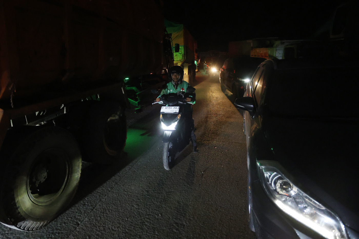 Pengguna sepeda motor melintasi jalur yang di lewati truk yang menyebabkan kemacetan di Parung Panja