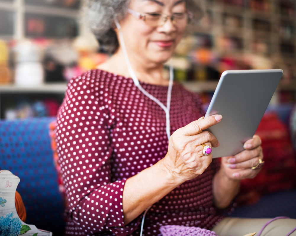 Ilustrasi seorang wanita berusia 70-an yang tersenyum saat menggunakan tablet atau ponsel pintar, menunjukkan keterlibatan dengan teknologi modern./Freepik - Image