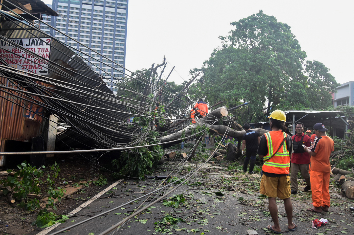 Petugas memotong batang pohon tumbang yang menutupi Jalan Jombang Raya, Pondok Aren, Tangerang Selat