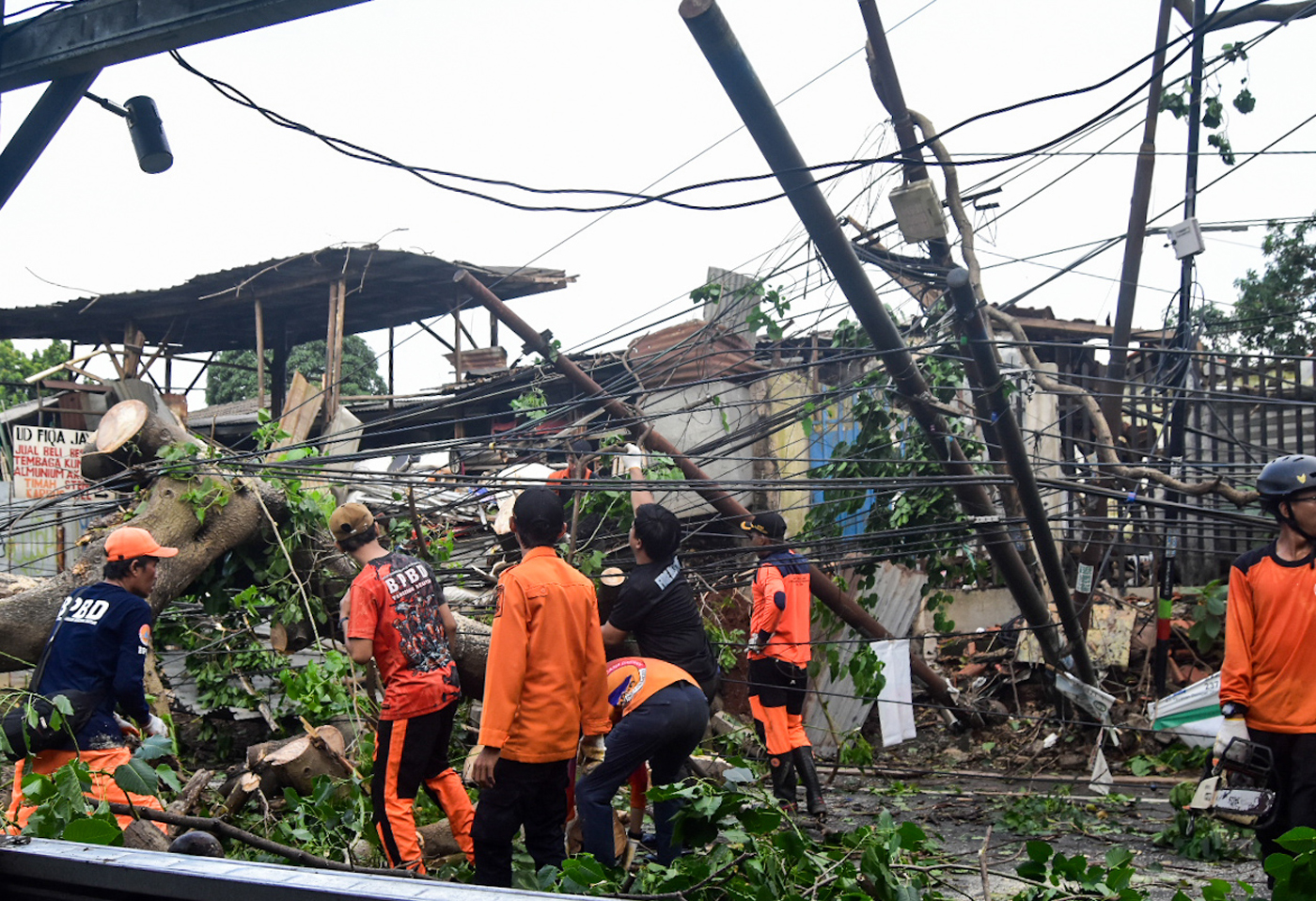 Petugas memotong batang pohon tumbang yang menutupi Jalan Jombang Raya, Pondok Aren, Tangerang Selat