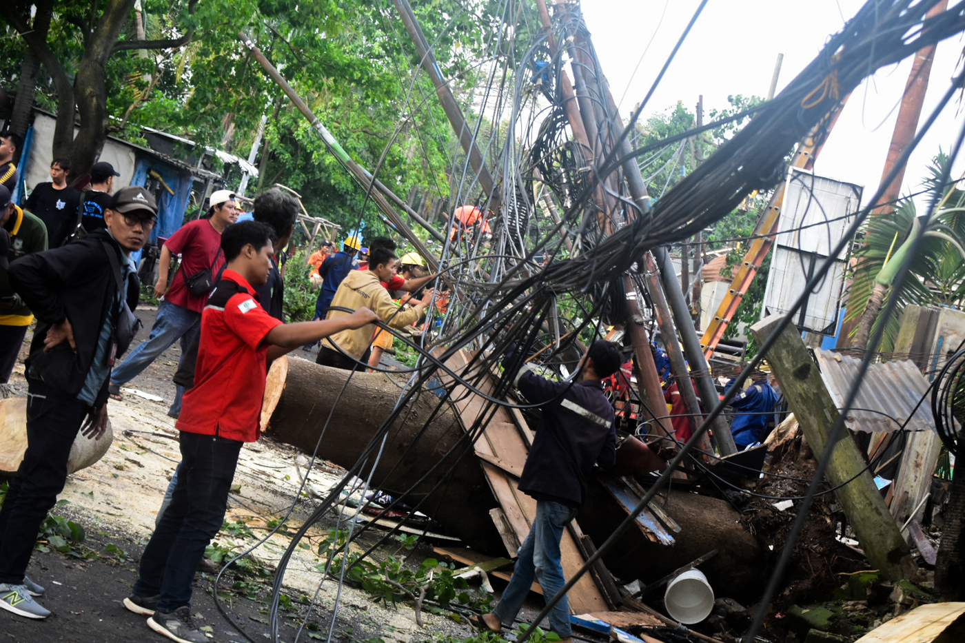 Petugas memotong batang pohon tumbang yang menutupi Jalan Jombang Raya, Pondok Aren, Tangerang Selat