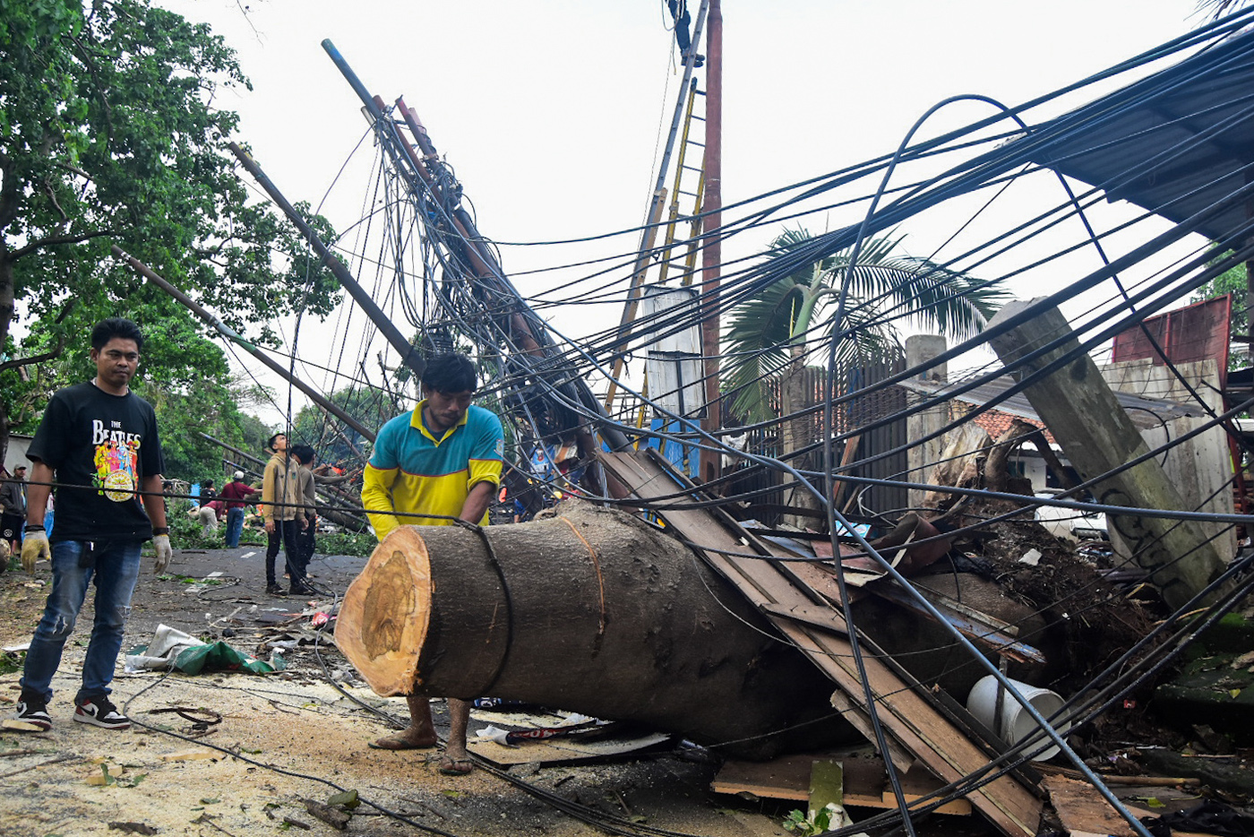 Petugas memotong batang pohon tumbang yang menutupi Jalan Jombang Raya, Pondok Aren, Tangerang Selat