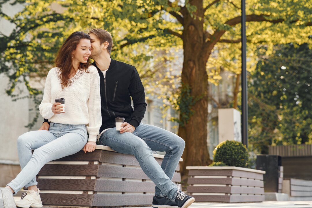 Sepasang kekasih duduk berdekatan dan bergurau di bangku taman, menikmati keheningan dan kebersamaan, sebuah tanda hubungan yang tulus dan tidak dipaksakan./Freepik - Image