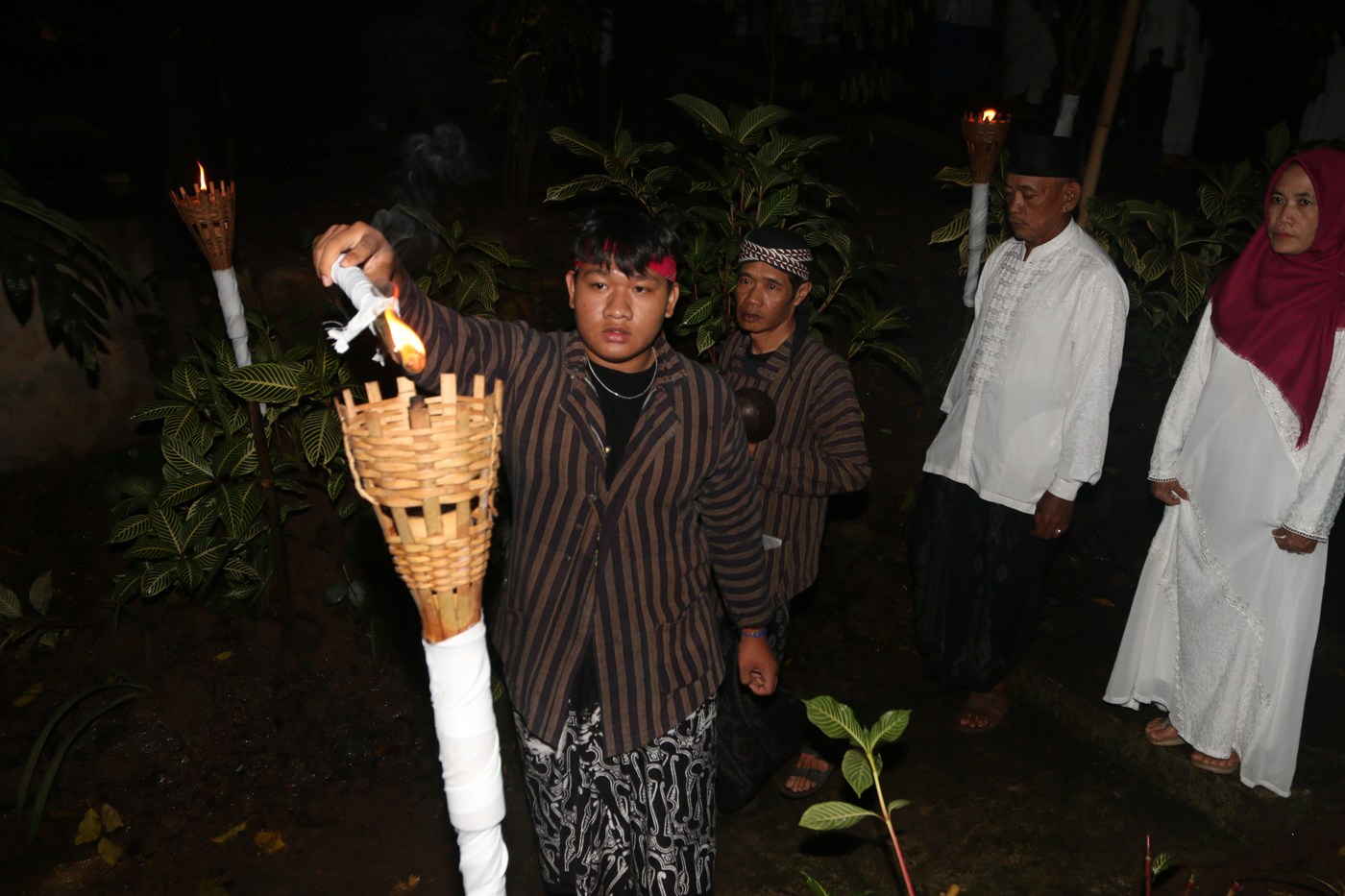 Sejumlah warga mengenakan pakaian tradisional membawa obor dan kendi berisi air dari sendang saat tr