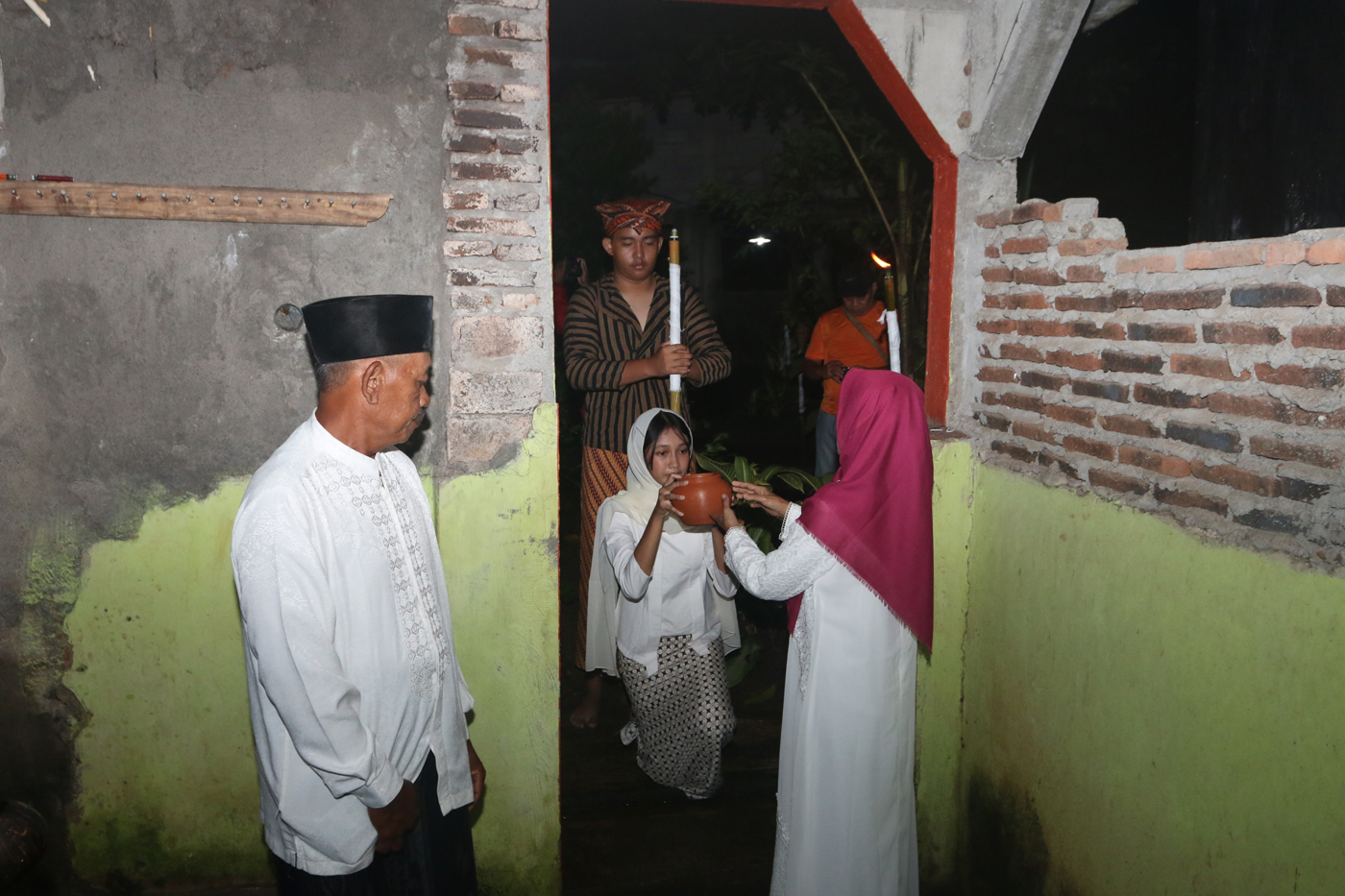 Sejumlah warga mengenakan pakaian tradisional membawa obor dan kendi berisi air dari sendang saat tr