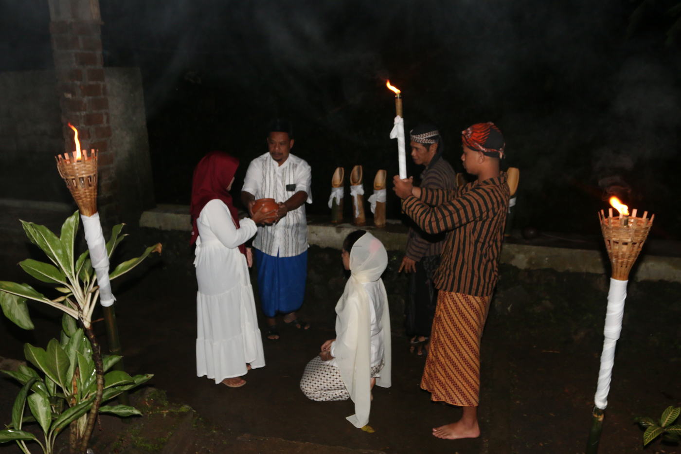 Sejumlah warga mengenakan pakaian tradisional membawa obor dan kendi berisi air dari sendang saat tr