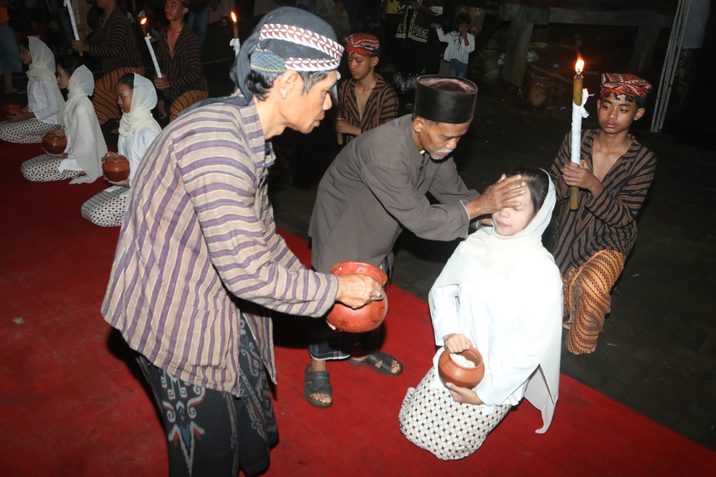 Sejumlah warga mengenakan pakaian tradisional membawa obor dan kendi berisi air dari sendang saat tr