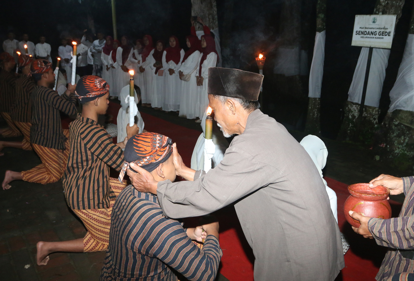 Sejumlah warga mengenakan pakaian tradisional membawa obor dan kendi berisi air dari sendang saat tr